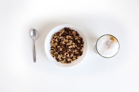 top view of glass of coffee latte and cornflakes in bowl with spoon in rowの写真素材