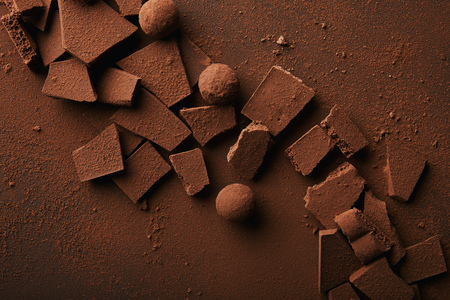 flat lay with arranged truffles and chocolate bars with cocoa powder on tabletopの写真素材