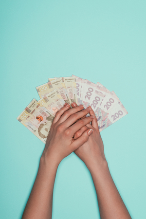 cropped shot of woman with bunch of cash isolated on turquoiseの写真素材