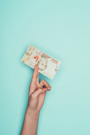cropped shot of woman holding ukrainian money isolated on turquoiseの写真素材