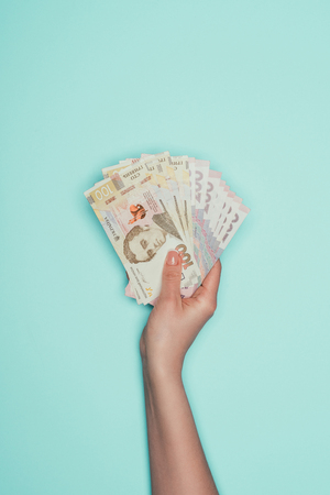 cropped shot of holding bunch of ukrainian cash isolated on turquoiseの写真素材