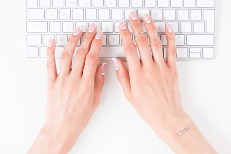 top view of female hands with beautiful manicure typing on keyboard の写真素材
