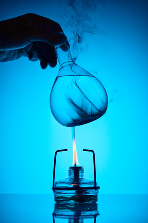 cropped image of chemist warming up substance for analysis