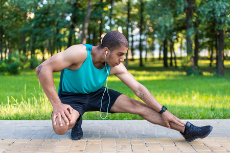 african american sportsman stretching in park