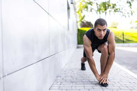 african american sportsman stretching on street