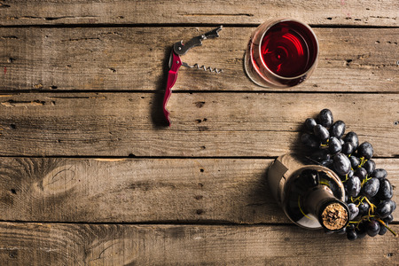 top view of bottle of pink wine, corkscrew, wineglass and grapes on wooden tabletop with copy space の写真素材