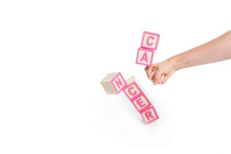 close-up partial view of fist breaking cubes with word cancer isolated on whiteの写真素材