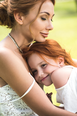 mother and daughter hugging in parkの写真素材