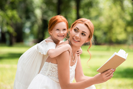 mother and daughter reading book at parkの写真素材