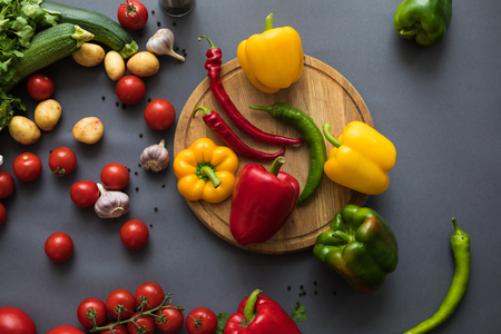 top view of fresh ripe vegetables on wooden cutting board on greyの写真素材