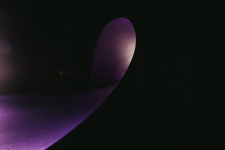 warping purple paper in shape of wave on blackの写真素材