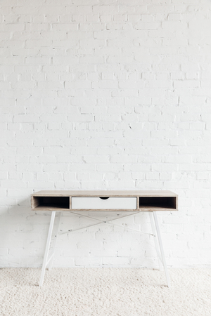 empty work table in front of white brick wallの写真素材