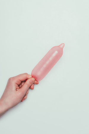 partial view of woman holding opened condom in handの写真素材