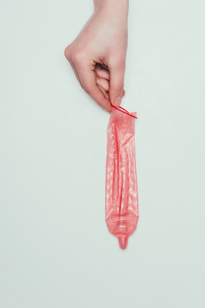 partial view of woman holding opened condom in handの写真素材