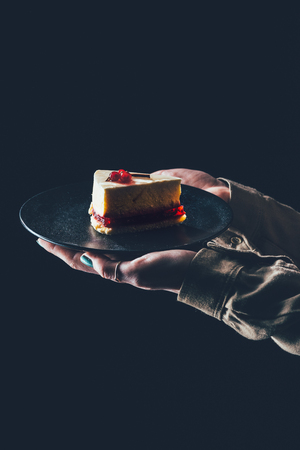 woman holding piece of homemade cake on plate in hands