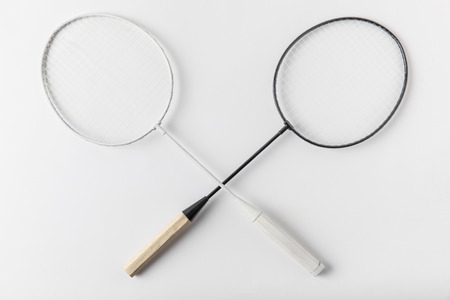 crossed badminton rackets on white surfaceの写真素材