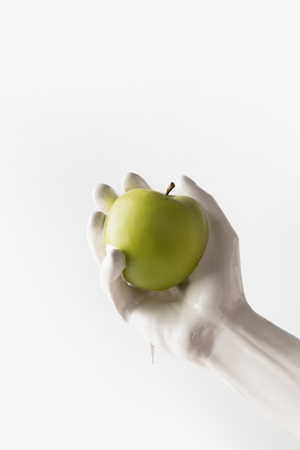 girl in white paint holding apple isolated on whiteの写真素材