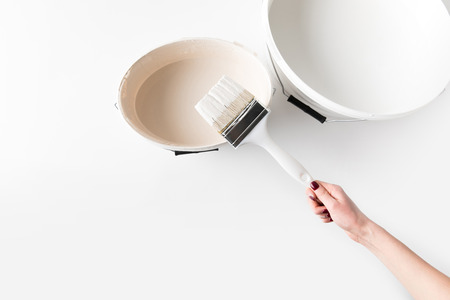 cropped image of girl holding brush in white paint on bucketの写真素材