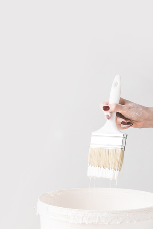 cropped image of woman holding brush in white paint above bucketの写真素材