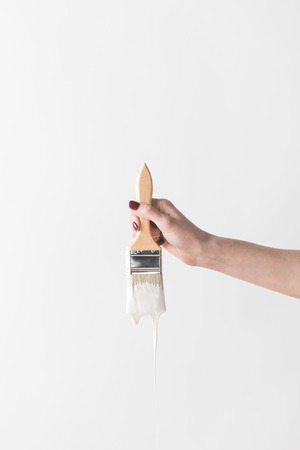 woman holding brush in white paint isolated on whiteの写真素材