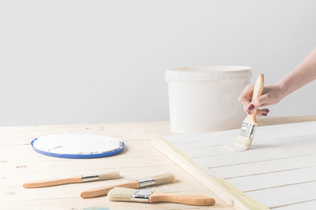 girl painting wooden surface with white paintの写真素材
