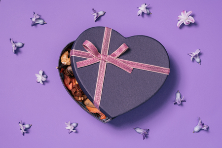 heart shaped gift box with flowers around isolated on purpleの写真素材