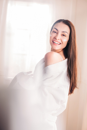 Young woman in bathrobe with cream on faceの写真素材