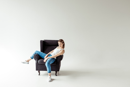 woman in singlet sitting on armchairの写真素材