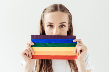 woman covering mouth with rainbow flagの写真素材