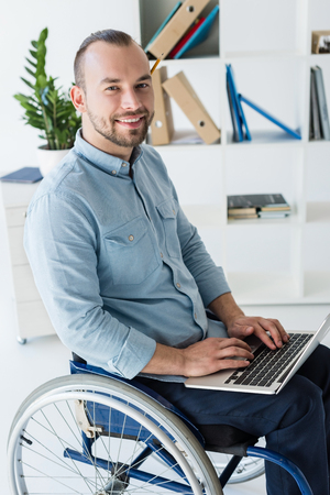 businessman in wheelchair using laptopの写真素材