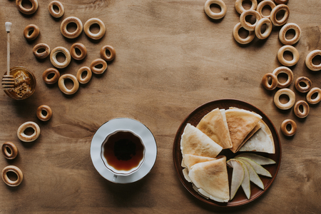 top view of tasty homemade pancakes with cup of tea, bagels and honeyの写真素材