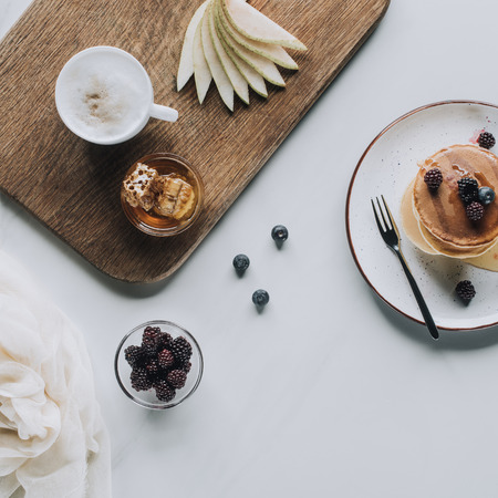 top view of delicious homemade pancakes with berries and honey on greyの写真素材