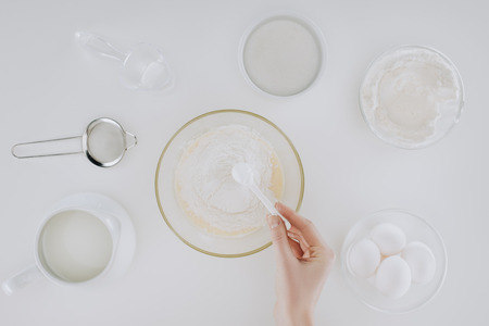 cropped shot of person preparing dough while cooking pancakes isolated on grey