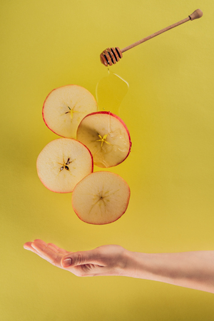 partial view of female hand and levitating pieces of apple with honeyの写真素材