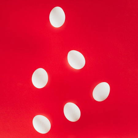 close up view of raw chicken eggs isolated on redの写真素材