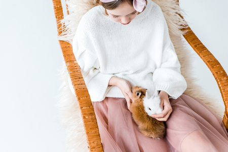 girl with cute furry bunnies sitting in rocking chairの写真素材