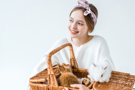 adorable happy girl holding basket with cute furry rabbitsの写真素材