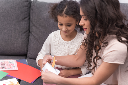 mother and daughter cutting paper for greeting card on mothers dayの写真素材