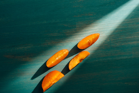 top view of persimmon persimmon pieces on table with light and shadowの写真素材