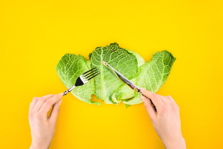 cropped shot of person eating healthy savoy cabbage isolated on yellowの写真素材