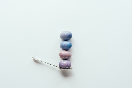 top view of four painted easter eggs on spoon isolated on white