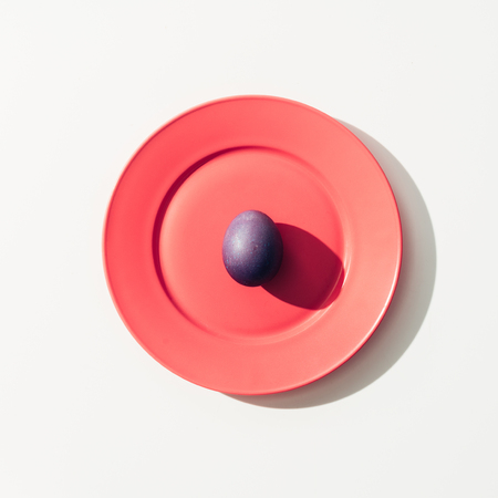 top view of purple easter egg on red plate, on whiteの写真素材