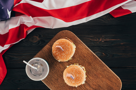 top view of arranged burgers and soda drink with american flag on wooden tabletop, presidents day celebration conceptの写真素材