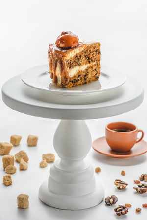 piece of delicious caramel cake on white cake stand, coffee on tableの写真素材