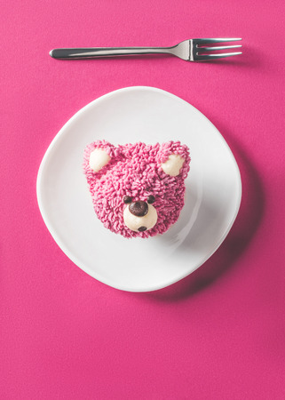 top view of cupcake in shape of bear head on plate on pink surfaceの写真素材