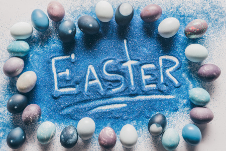 top view of easter sign made of blue sand with painted eggsの写真素材