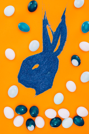 top view of bunny made of blue sand and easter eggsの写真素材