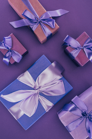 top view of decorative gift boxes with ribbons and bows on purpleの写真素材