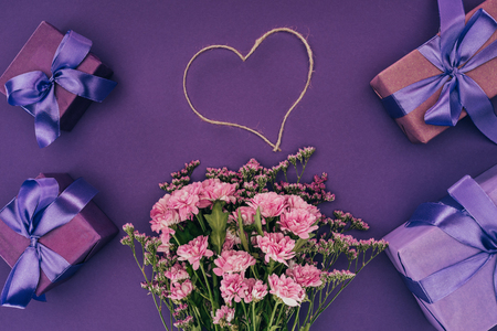 bouquet of beautiful pink flowers, heart-shaped rope and gift boxes on violetの写真素材