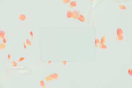 top view of beautiful tender rose petals with ribbon and blank card on grey   の写真素材